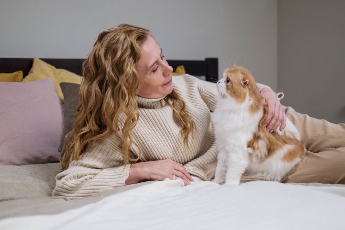Frau mit roter Katze auf dem Bett